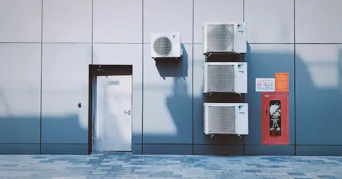 Air handling units mounted in a concrete wall next to a door