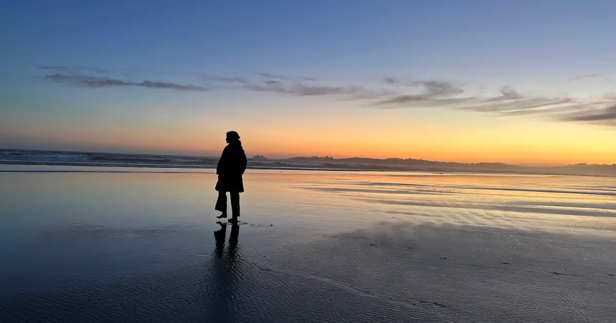 Girl walking on the beach at sunset in Tofino, Canada