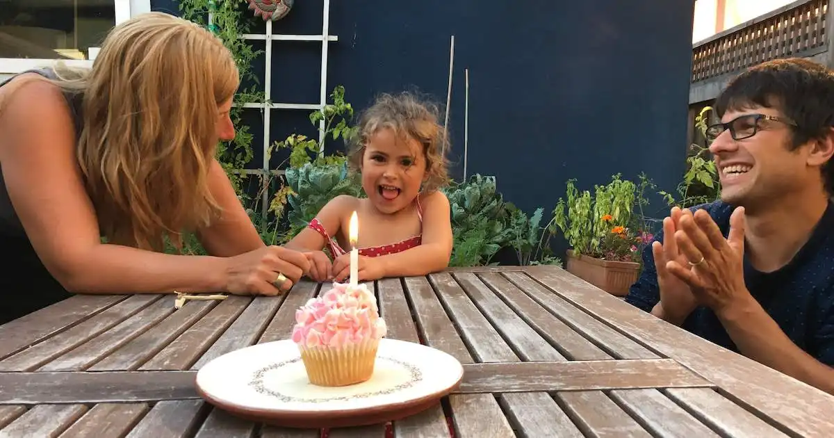 Cute little girl celebrating her birthday with a pink cupcake